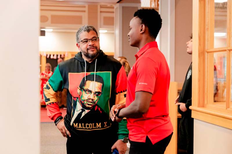 a man in a red shirt talking to another man