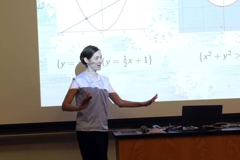 a woman standing in front of a large screen