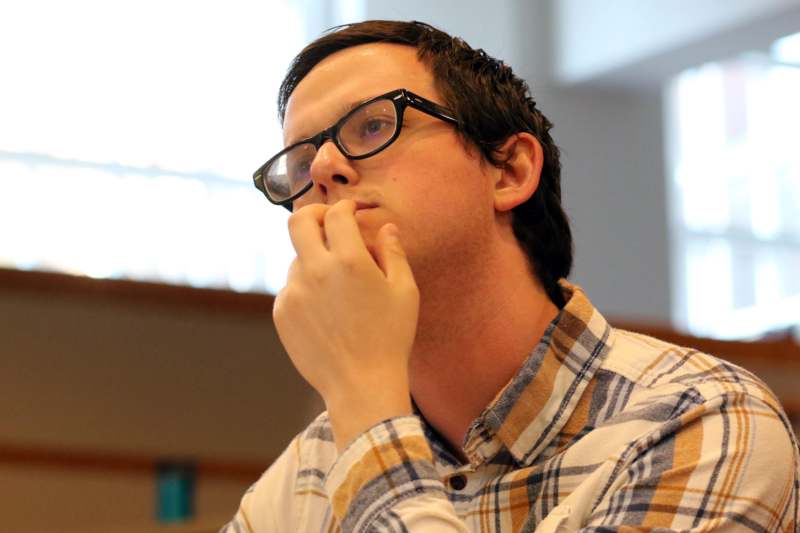 a man with glasses holding his hand to his chin