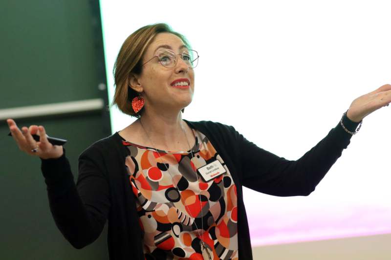 a woman in glasses holding her hands up