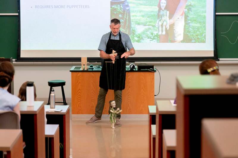 a man in an apron standing in front of a projection screen