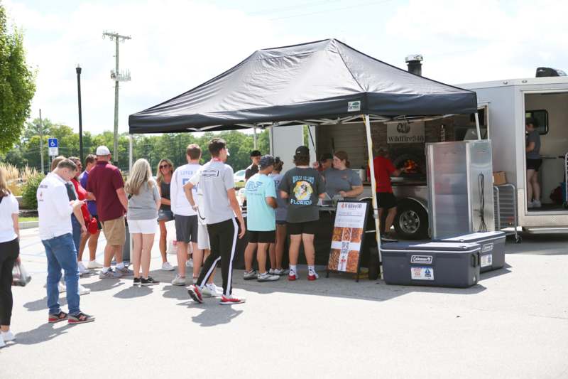 a group of people standing in front of a food stand