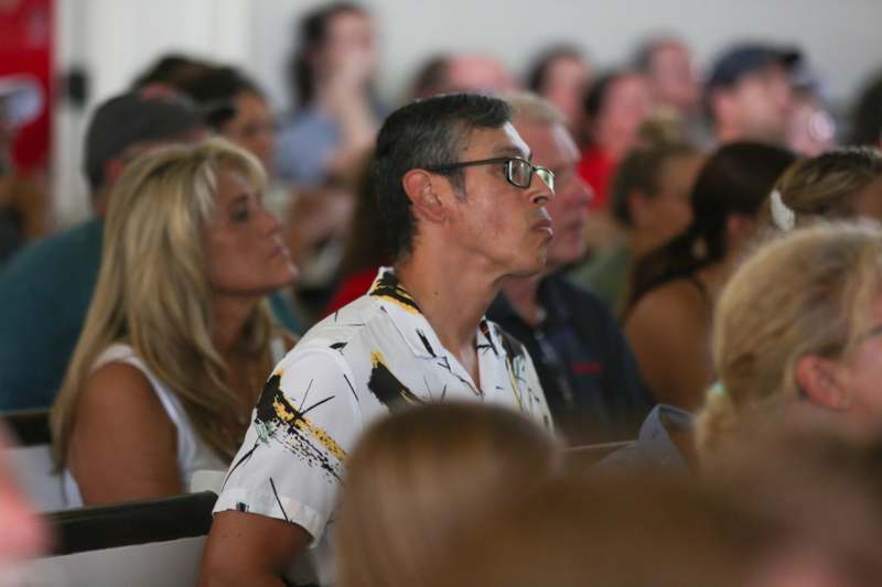 a man in a white shirt sitting in a room with people