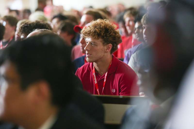 a man in a red shirt sitting in a room with people