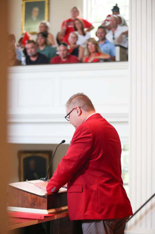 a man in a red suit at a podium with a microphone