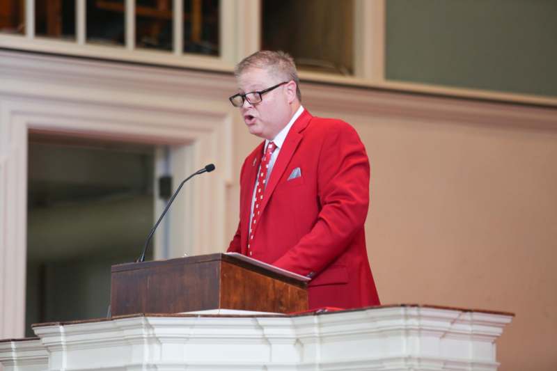 a man in a red suit standing at a podium