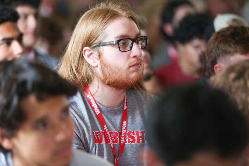 a man with red hair wearing glasses and a lanyard