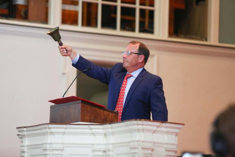 a man in a suit holding a bell