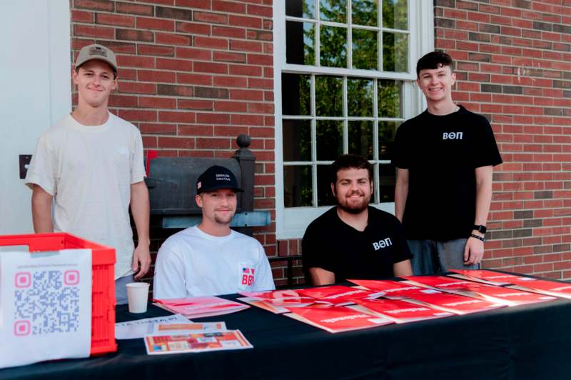 a group of men standing in front of a table with red posters