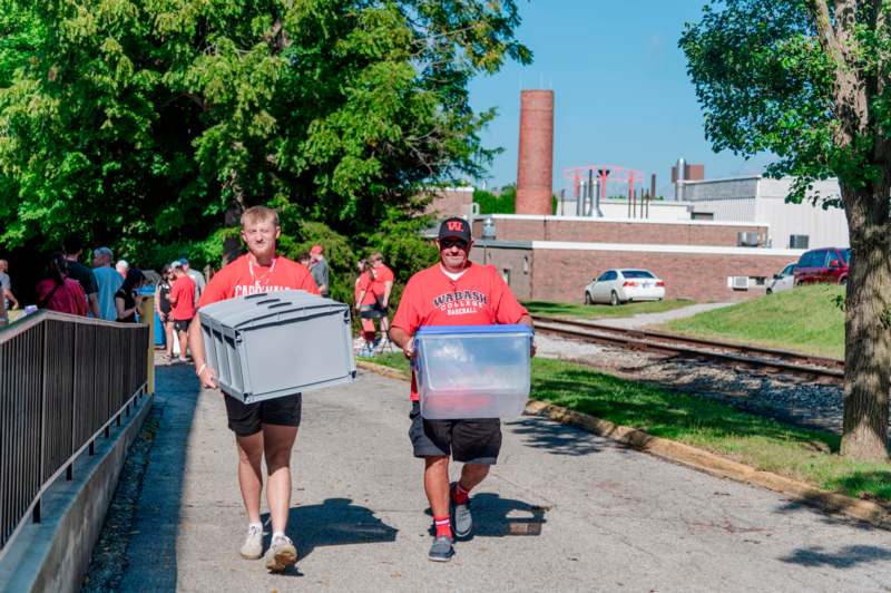 two men carrying boxes on a sidewalk