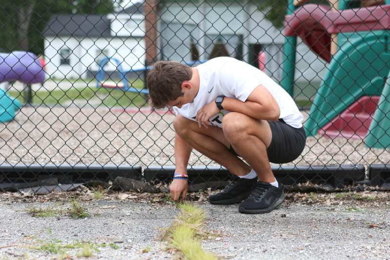 a man crouching down on a fence