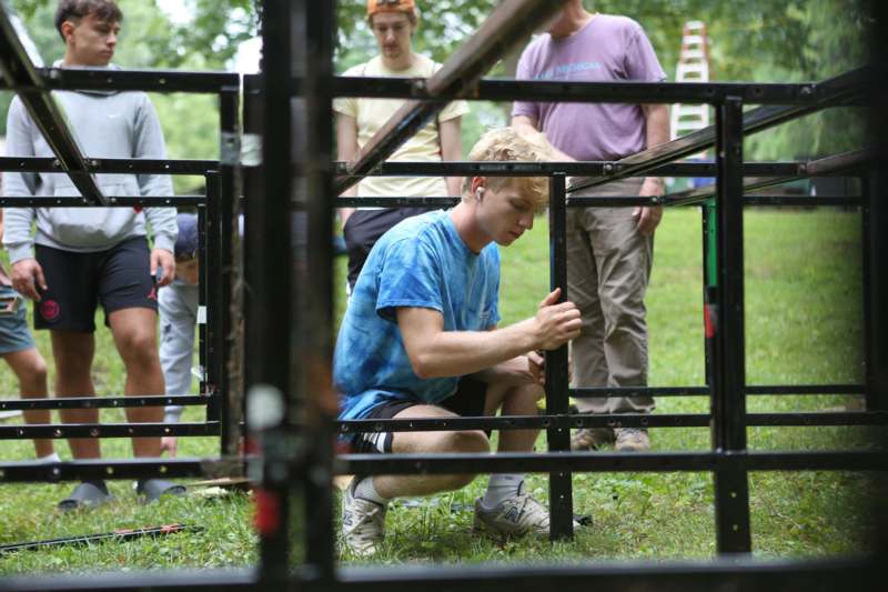 a man in blue shirt and shorts kneeling in front of metal bars