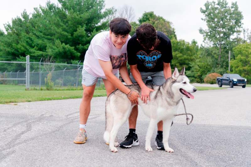 two men petting a dog