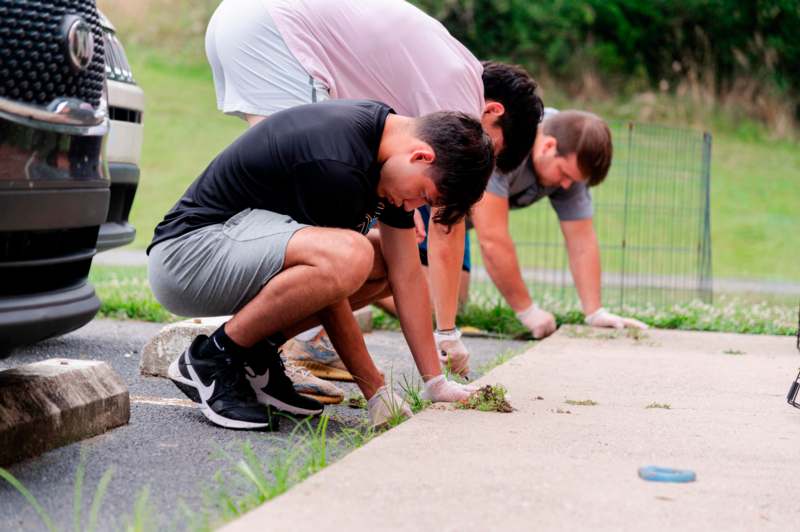 a group of men squatting on a sidewalk