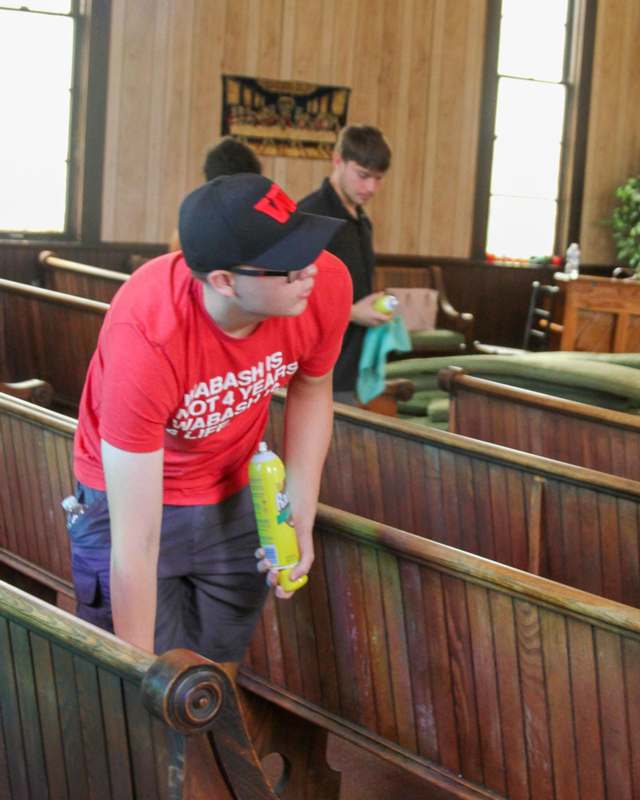 a man holding a spray bottle in a church pew