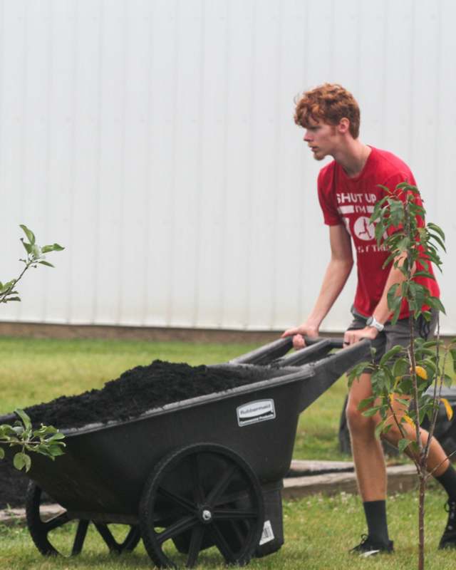 a man pushing a wheelbarrow full of dirt