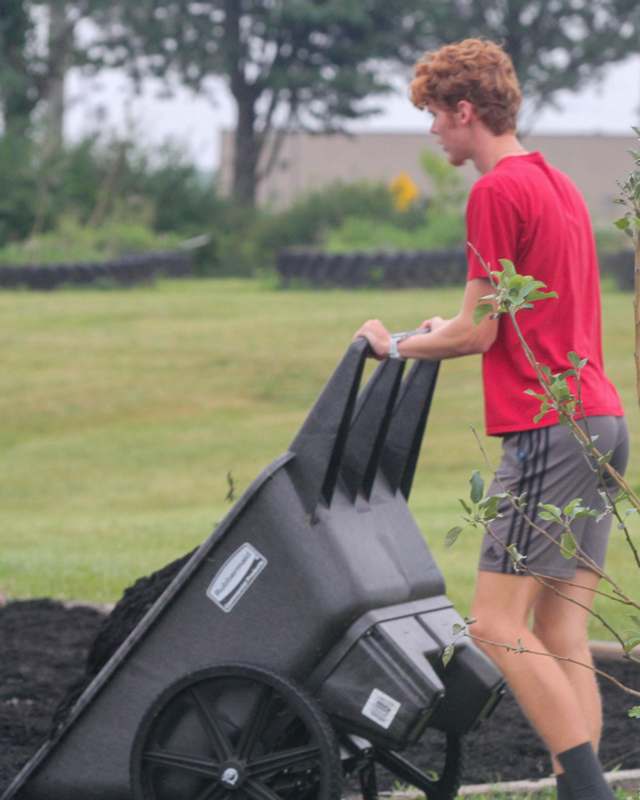 a man pushing a wheelbarrow full of dirt