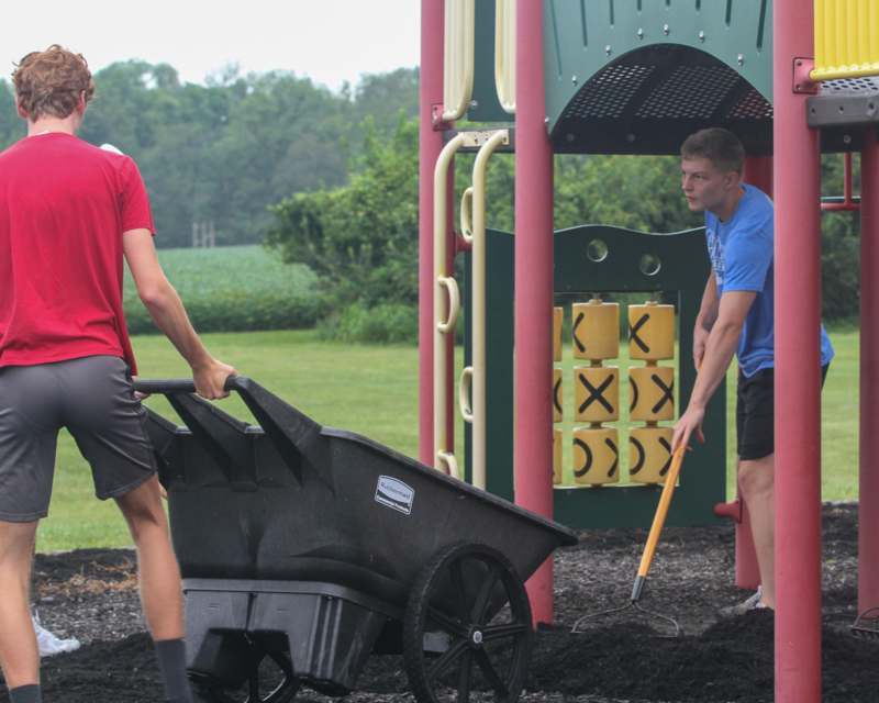 a man pushing a wheelbarrow with a woman in a playground