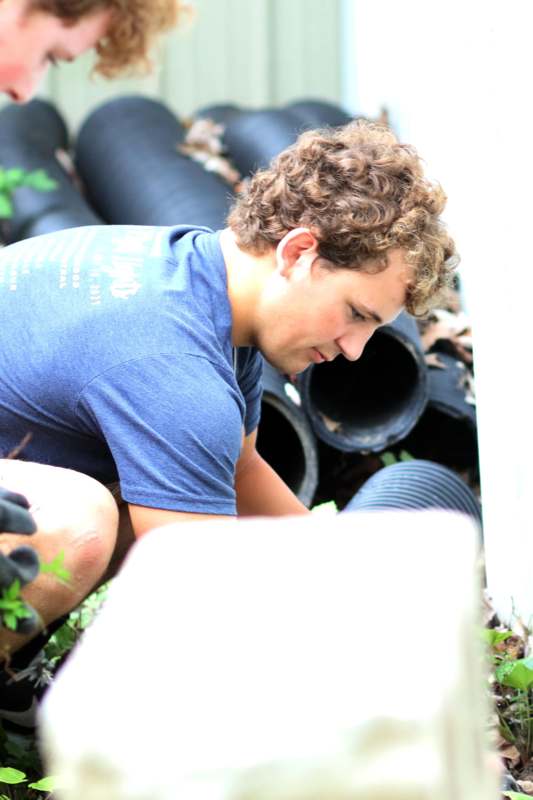 a man kneeling next to black pipes