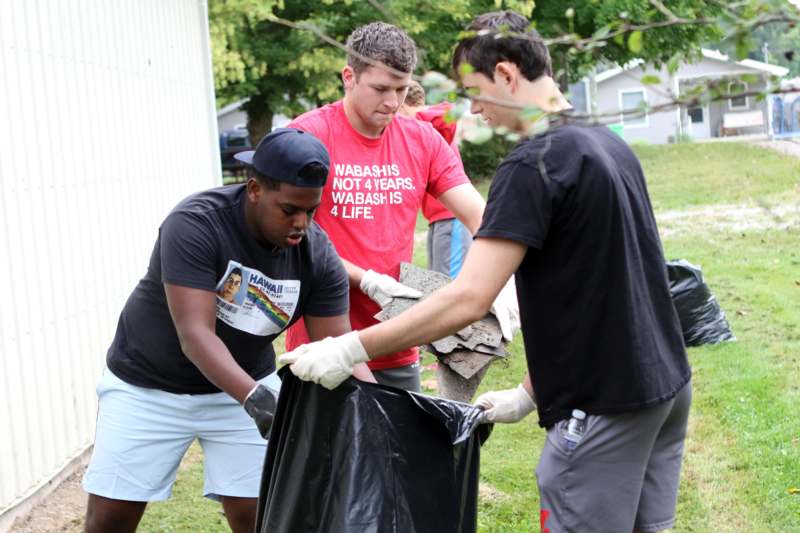 a group of people putting garbage in a bag