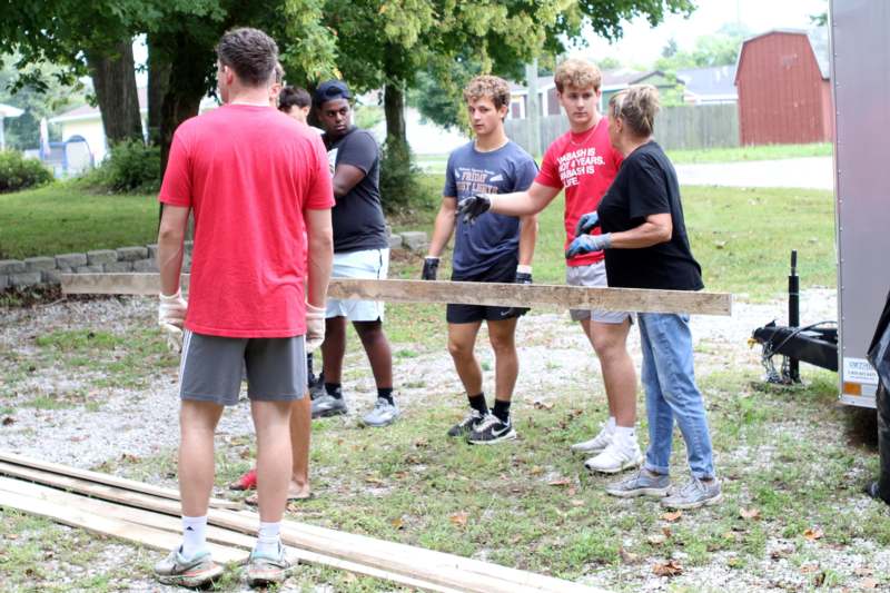 a group of people standing around a wood plank