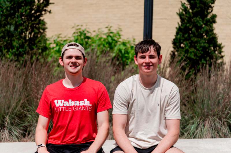 two men sitting on a sidewalk