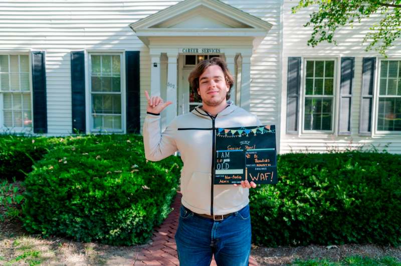 a man holding a sign in front of a white house