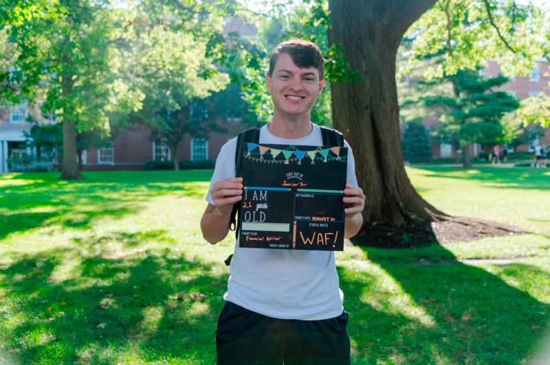 a man holding a sign in front of a tree