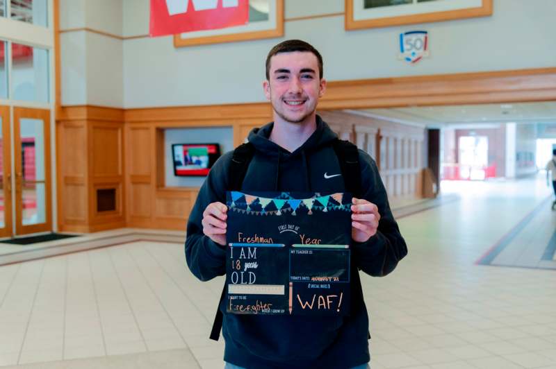 a man holding a sign in a hallway