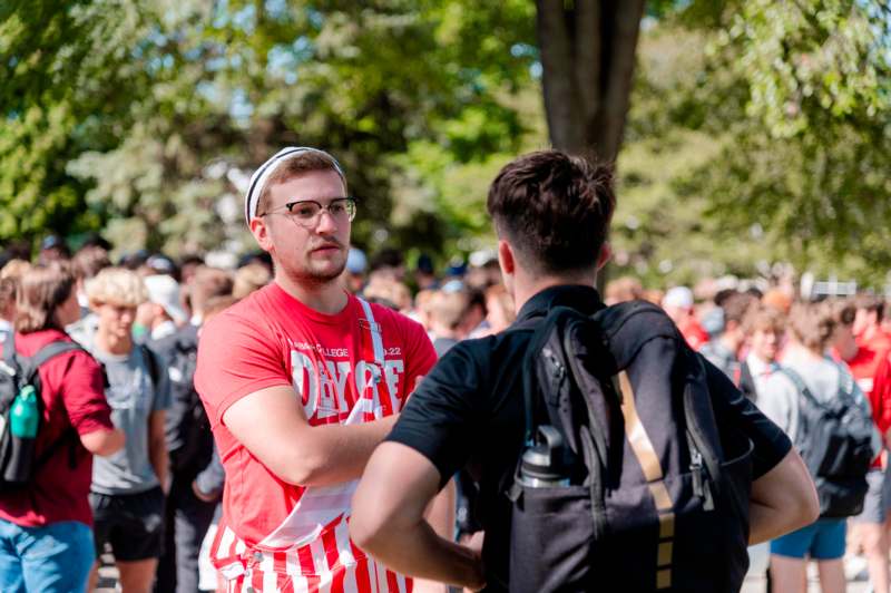 a man in a red and white striped shirt standing in a crowd of people