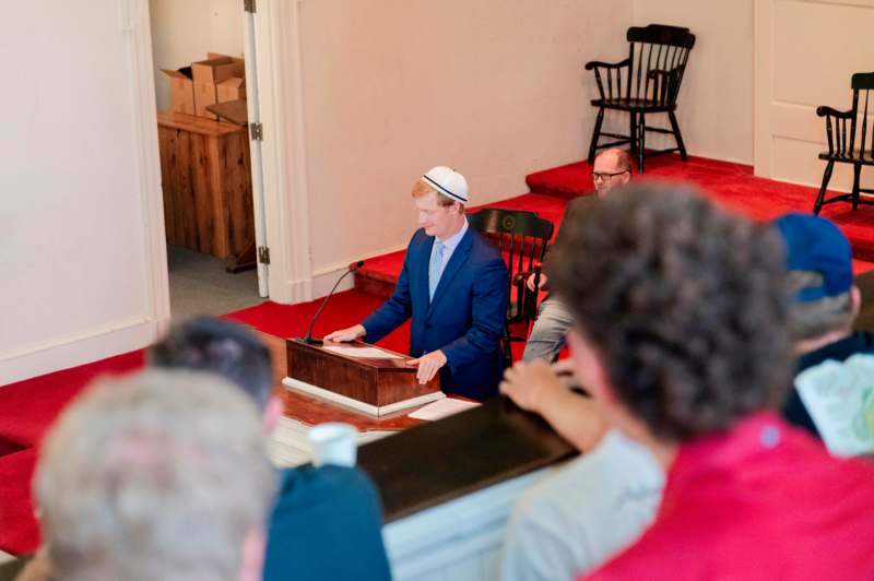 a man in a blue suit and white hat speaking at a podium