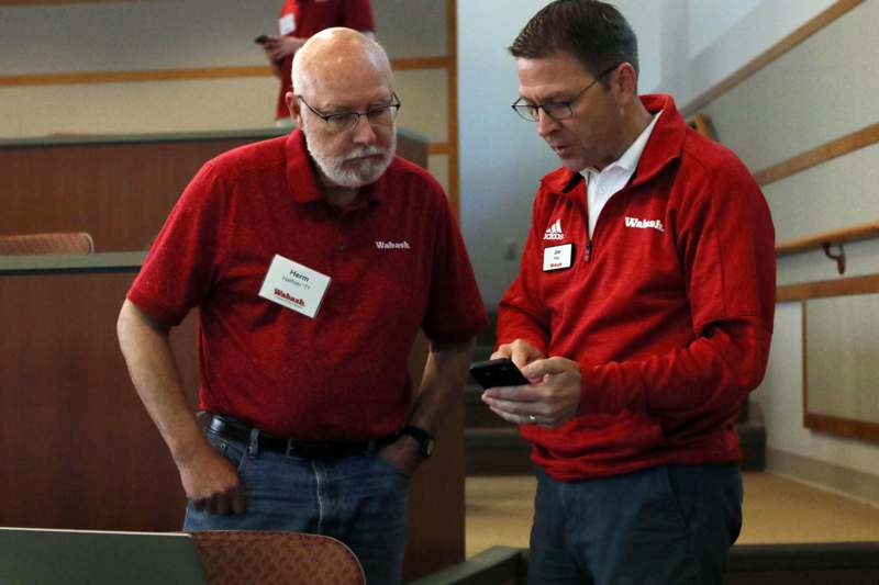 men in red shirts looking at a cellphone