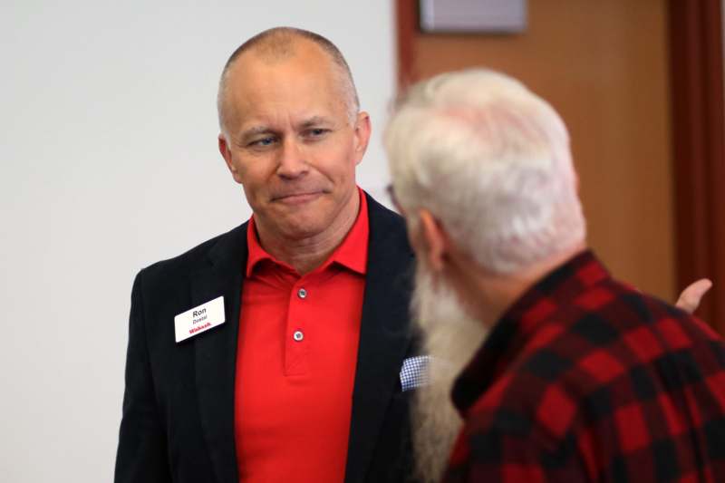 a man in a suit and red shirt talking to another man