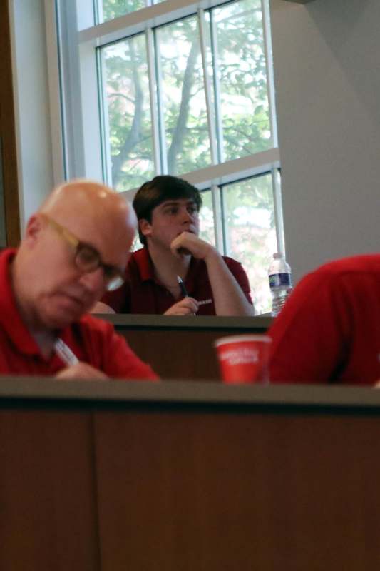 a man in red shirt sitting in a classroom