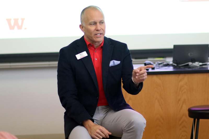 a man in a suit sitting and pointing