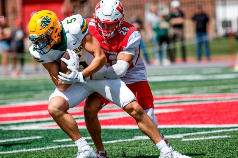 a football player in a helmet holding another football player in a tackle