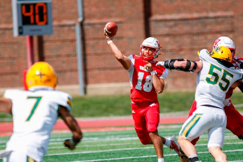 a football player in a red uniform throwing a football