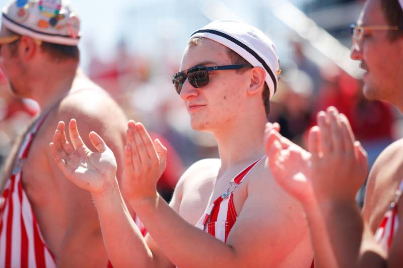 a man in a bathing suit and sunglasses clapping