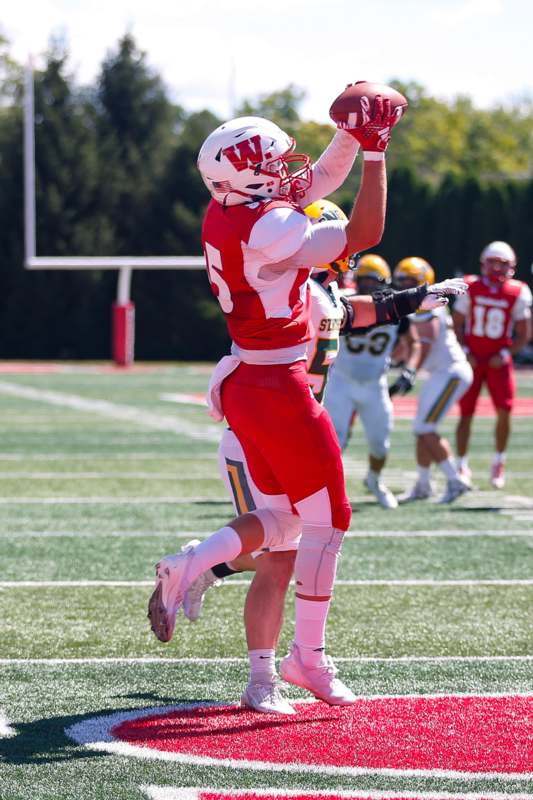 a football player in a red uniform holding a football