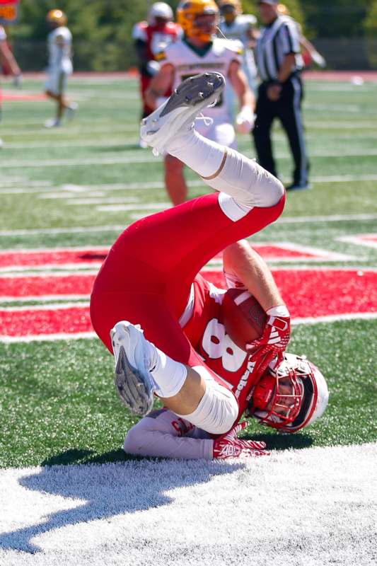 a football player in red uniform on the ground with his leg up