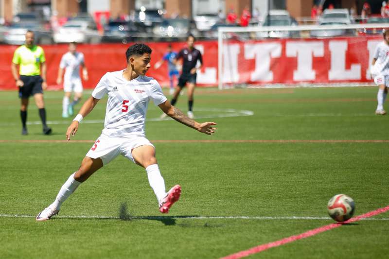 a man in a white uniform kicking a football ball