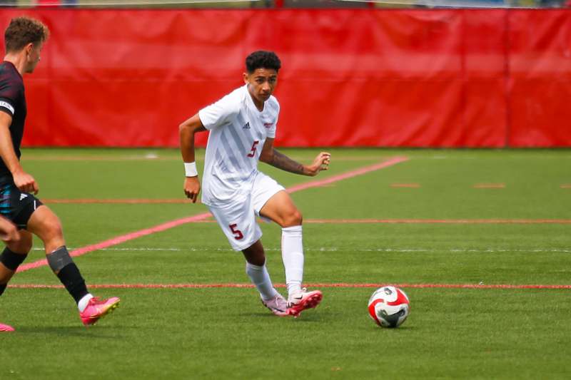 a man in a white uniform kicking a football ball