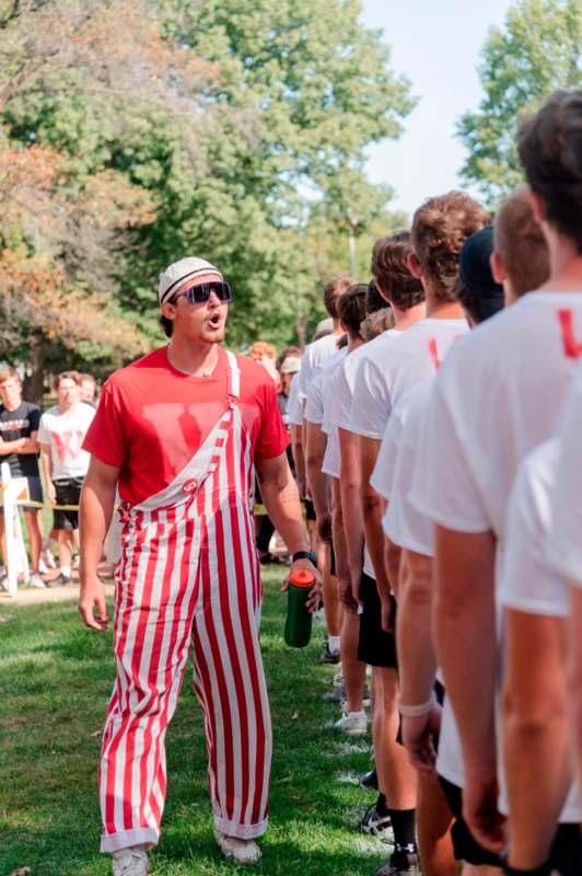 a man in red and white striped overalls standing in a line of people