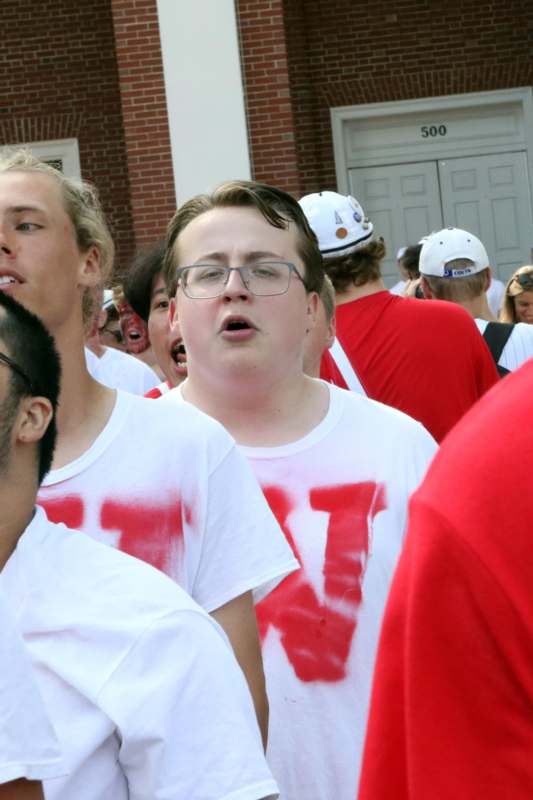 a man wearing glasses and a red shirt with a white hat