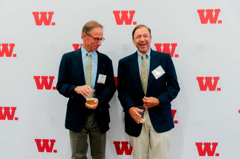 two men standing in front of a wall with red letters