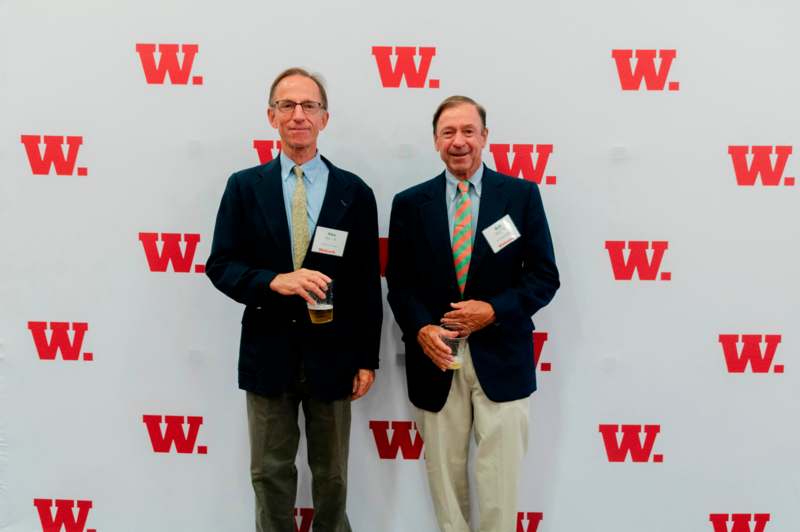 two men standing in front of a wall with red letters