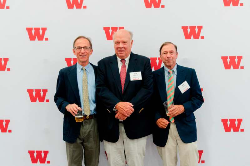 a group of men standing in front of a wall with red letters