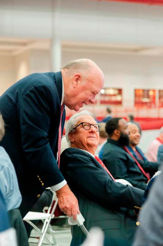 a man in a suit leaning over another man