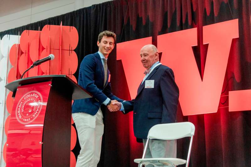 a man shaking hands with another man at a podium