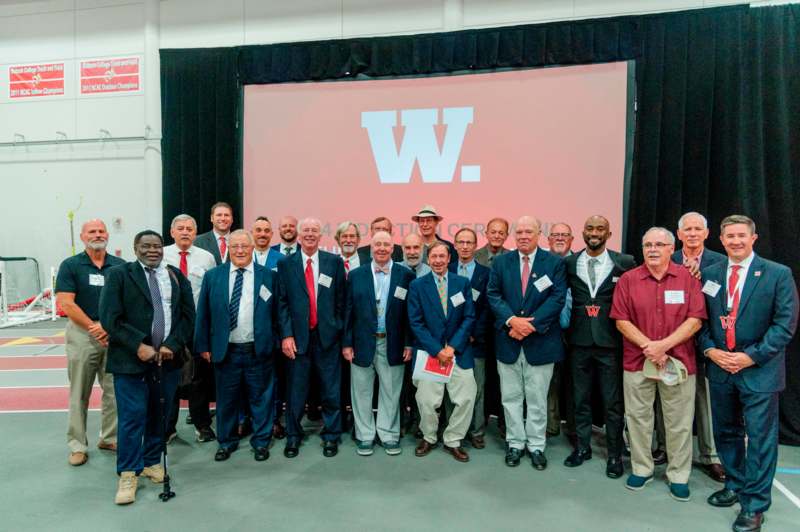 a group of men standing in front of a large screen